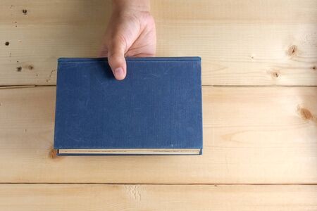 Hands hold book on wood tableの写真素材