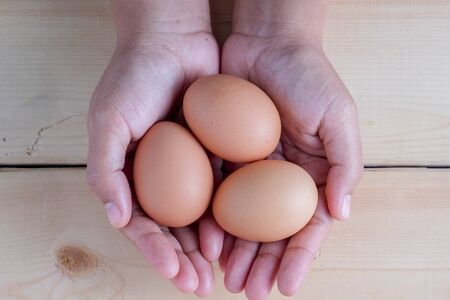 hand holding egg on wooden background