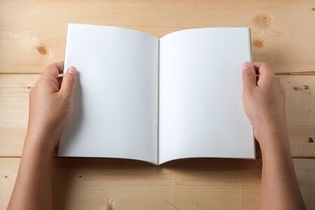 Hands hold book on wood table