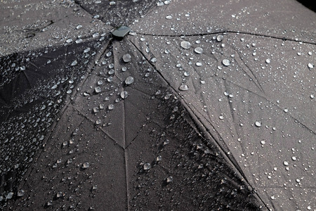 Rain drops falling from a black umbrellaの写真素材