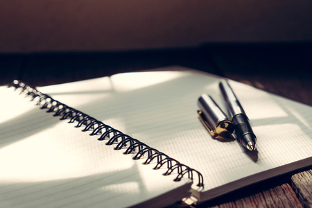 pen and book on wood background with filter effect retro vintage style