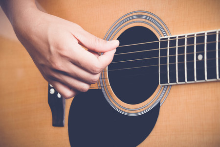 woman's hands playing acoustic guitar with filter effect retro vintage style
