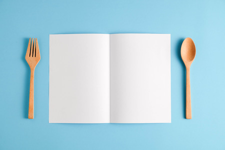 Wooden spoon and white paper on a blue background, for a food menu background.の写真素材