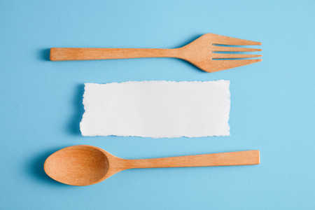 Wooden spoon and white paper on a blue background, for a food menu background.の写真素材