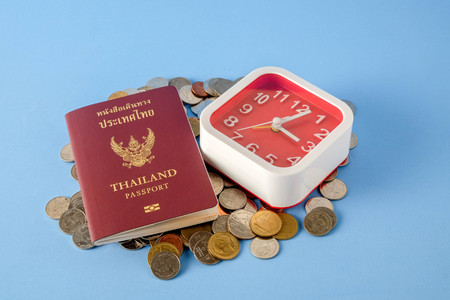 Thailand passport  brown cover and money coin on blue paper background for traveling on holidaysの写真素材