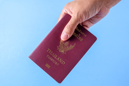 Thailand passport  brown cover  on blue paper background for traveling on holidaysの写真素材