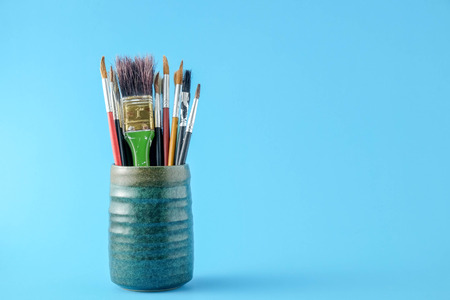 Row of artist paint brushes close up on blue  backgroundの写真素材