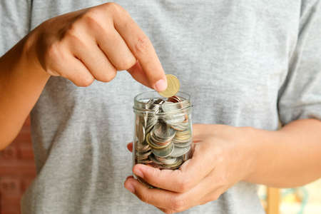 save money for investment concept Hand holding money in jarの写真素材