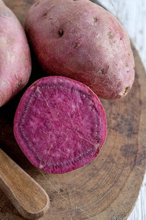 Raw sweet potatoes on wood background with filter effect retro vintage styleの写真素材
