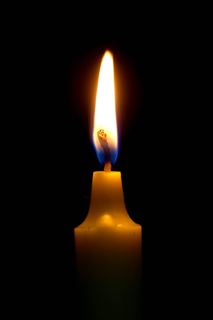 One light candle burning brightly on black background.の写真素材