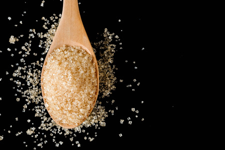 Brown sugar in wood spoon on black background.Components of The food is sweet delicious.の写真素材