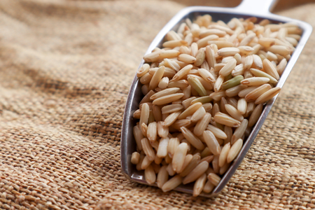 Raw brown rice in a spoon and bowl. top view food backgroundの写真素材