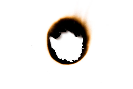 burnt holes in a piece of paper isolated on white backgroundの写真素材