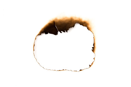 burnt holes in a piece of paper isolated on white backgroundの写真素材