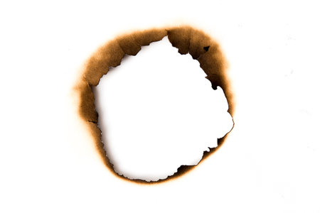 burnt holes in a piece of paper isolated on white backgroundの写真素材