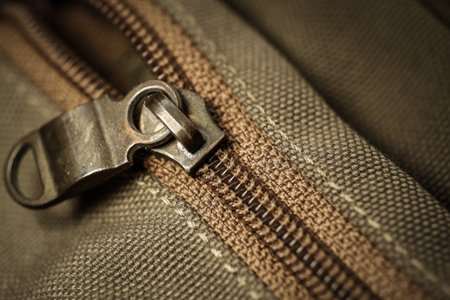 Close-up of an old zipper on a dark green cloth
