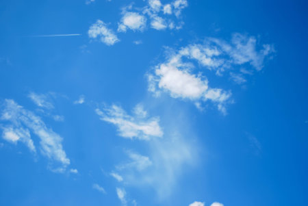 Beautiful clear blue sky and white clouds background   with trail white smoke from the airplane.