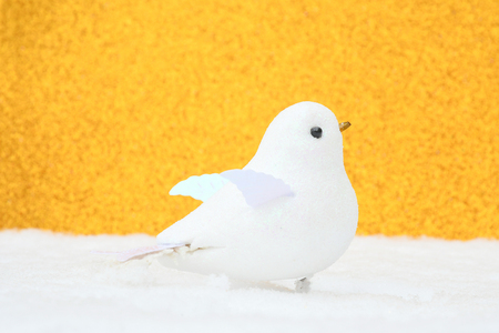 Soft focus whit toy bird put on white snow with orange gilter background, idea card for invitation for christmast or new year party.の写真素材