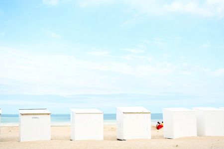 Row of small beautiful cabins in white, black and soft blue install on beach for service to tourist on holiday with background aqua blue sea and small white wave, blue sky and white clouds.の写真素材