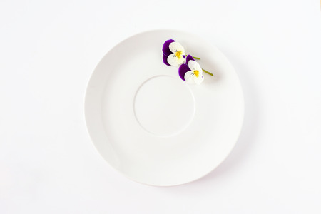 Sweet pansy flowers decorate on empty white circle dish on white background isolated, concept for food style and decoreated special meal in party.の写真素材