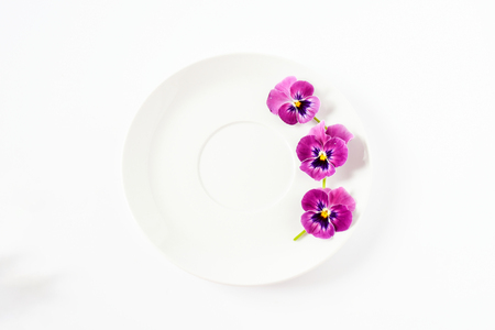 Sweet pansy flowers decorate on empty white circle dish on white background isolated, concept for food style and decoreated special meal in party.の写真素材