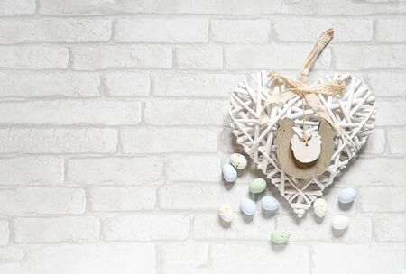 Easter background flat lay with pastel chocolate eggs and white heart nature wood figure on white...