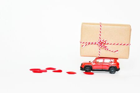 Selecitive focus miniature red car ,present heart box and red heart on white background, copy space. Idea surprise gift for special day as valentine's day, anniversary, birthday concept.の写真素材