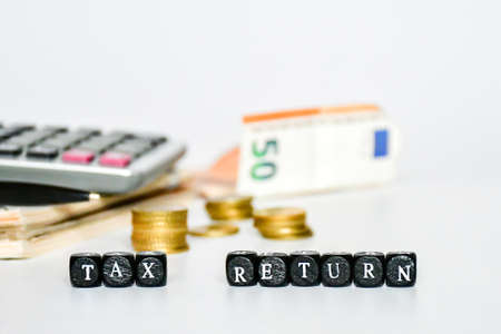 Selective focus small black box with alphabet TAX, coin, calculator on white background. Process of tax time and finance background concept.の写真素材