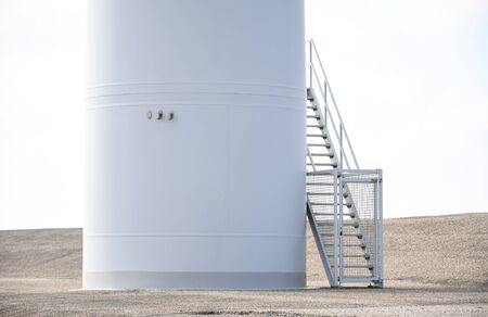 Background a part of white turbeine windmill with metal stair and cement floor ,white sky. Space for...