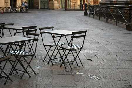 Empty  terrace with tables and chairs in wood and metal at coffee and resteurant beside sidewalk in center city. Environment city life during confinement due to corona virus or covid-19  Background business dramatic scene conept.の写真素材