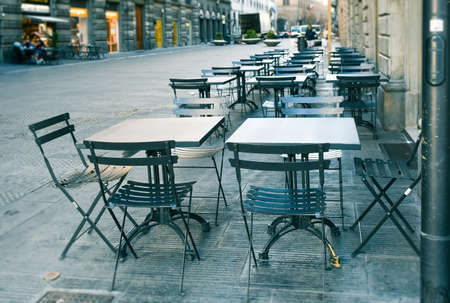 Empty  terrace with tables and chairs in wood and metal at coffee and resteurant beside sidewalk in center city. Environment city life during confinement due to corona virus or covid-19  Background business dramatic scene conept.の写真素材