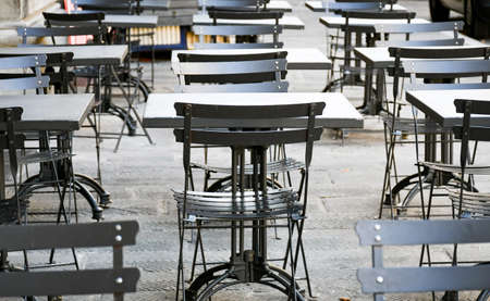 Empty  terrace with tables and chairs in wood and metal at coffee and resteurant beside sidewalk in center city. Environment city life during confinement due to corona virus or covid-19  Background business dramatic scene conept.の写真素材