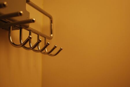 Metal hanger or hooker in wardrobe with yellow lighting in hotel. space for text . Grain noise effect.の写真素材