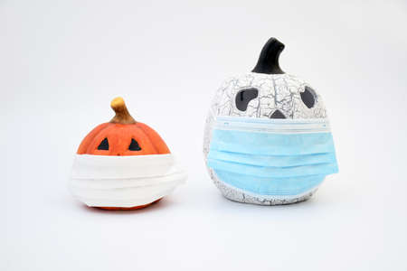 Object, ceramic pumpkin wearing a protective medical mask on white background. Infor for autumn...