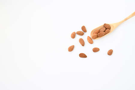 Selective focus raw peel almond seeds in bamboo spoon on white background with space for text.の写真素材