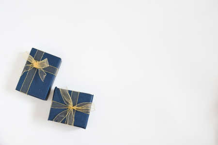 Christmas gift boxes wrap with blue navy paper and golden ribbon on white background with space for...