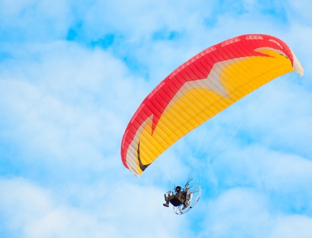 man with paraglider flies in the blue skyの写真素材