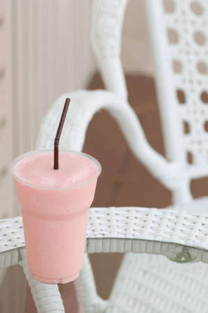 strawberries milk shake with white chair in the outdoor cafe