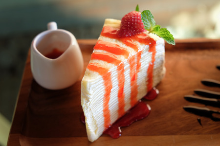 crape cake decorated with strawberry on top and strawberry sauceの写真素材