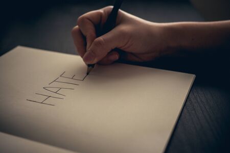 Hate concept - hand writing hate on book with toneの写真素材