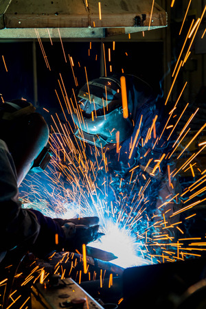 Welder working in a steel factory with sparks flying