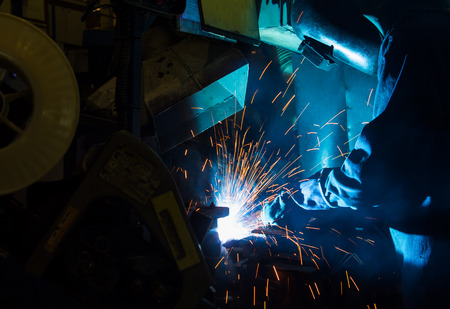 worker with protective mask welding metal