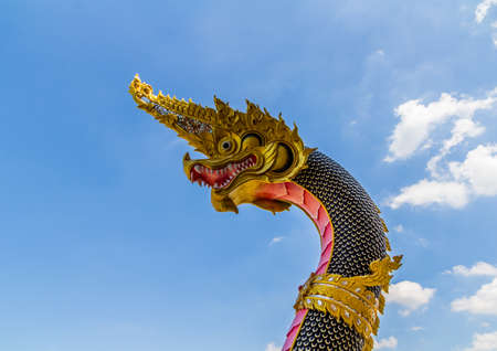 The Big Naga snake guarding Thai temple with white cloud and blue sky backgroundの写真素材