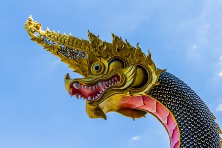 The Big Naga snake guarding Thai temple with white cloud and blue sky backgroundの写真素材