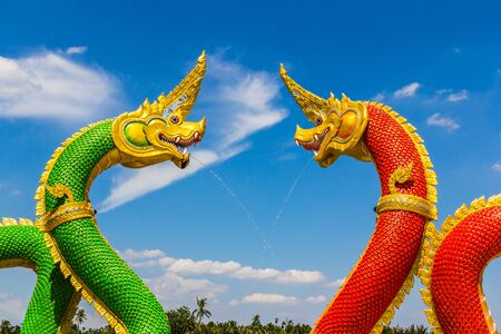 The Big Naga snake guarding Thai temple with white cloud and blue sky backgroundの写真素材