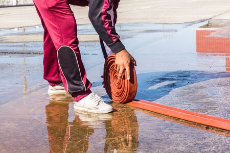The Man rolling up a fire hose after filled  Waterの写真素材