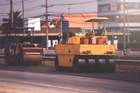 build paved road,Workers, roller and operating asphalt paver machine during road construction and...