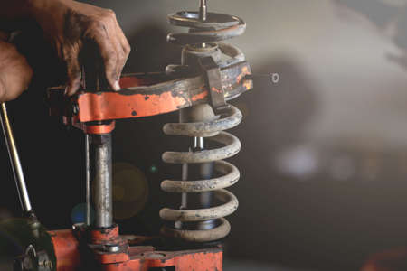 Shock Absorber ,Shock maintenance,Shock replacement,Car garage technician using spring compression tool to repair damaged shocksの写真素材
