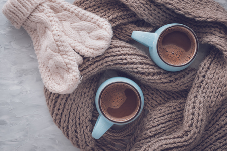 Christmas and New Year cozy holiday composition with scarf, mittens, mugs with cocoa or chocolate on the gray concrete background. Flat lay, top view.の写真素材