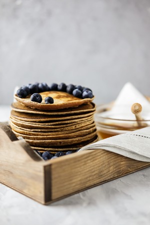 Homemade Chocolate Pancake with blueberries in a wooden tray on the linen napkin with honey. Food photography of a healthy morning breakfast.の写真素材